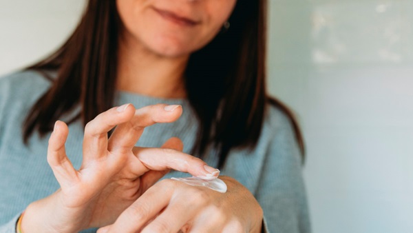 Une femme applique de la crème hydratante sur ses mains